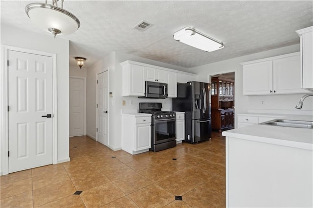 kitchen with visible vents, a sink, white cabinetry, appliances with stainless steel finishes, and light countertops