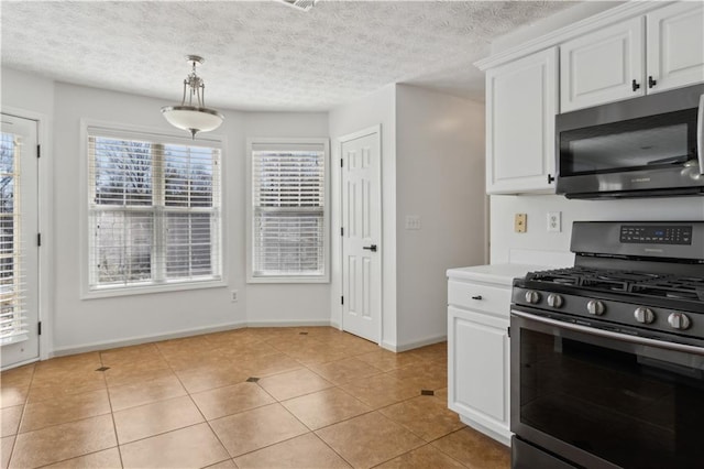 kitchen with light tile patterned floors, appliances with stainless steel finishes, white cabinets, and light countertops