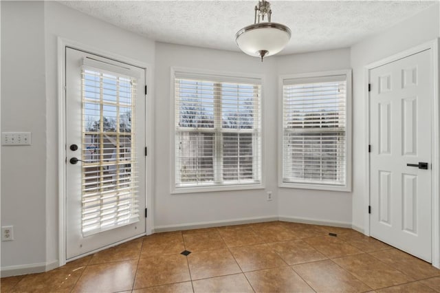 doorway featuring tile patterned floors, baseboards, and a textured ceiling