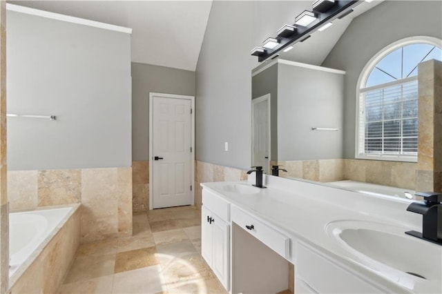 full bath with a sink, tile walls, a bath, and vaulted ceiling