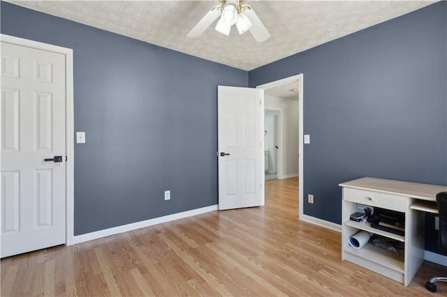 bedroom featuring baseboards, light wood finished floors, and a textured ceiling