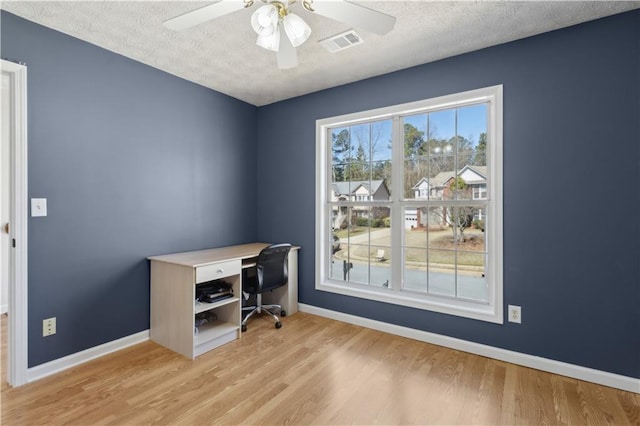 office featuring a ceiling fan, wood finished floors, baseboards, visible vents, and a textured ceiling