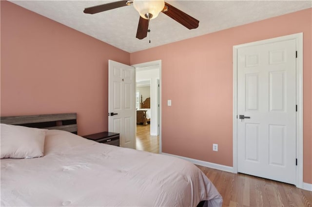 bedroom with light wood-type flooring, baseboards, a textured ceiling, and ceiling fan