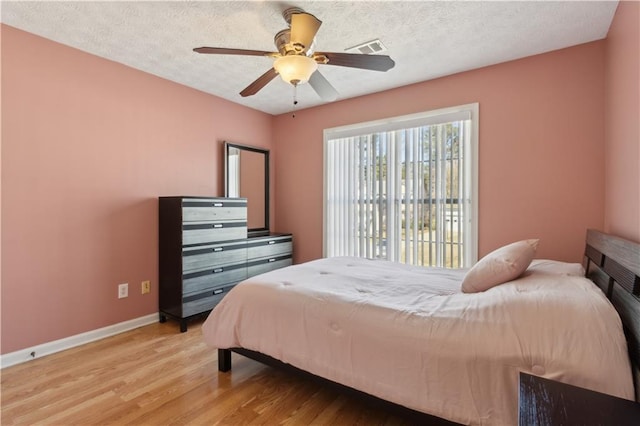 bedroom with baseboards, visible vents, ceiling fan, a textured ceiling, and light wood-type flooring