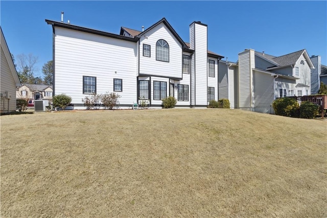 rear view of property featuring cooling unit, a chimney, and a yard