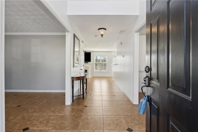 tiled entryway featuring a fireplace, a textured ceiling, and baseboards