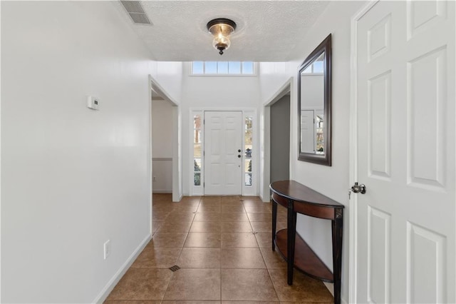 entrance foyer with tile patterned floors, baseboards, visible vents, and a textured ceiling