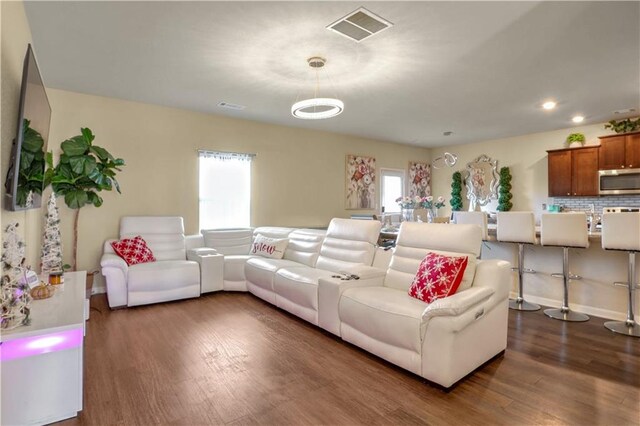 living room with a wealth of natural light and dark wood-type flooring