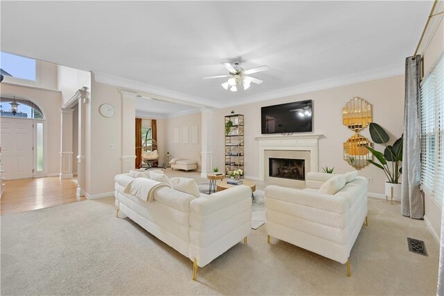 carpeted living room with crown molding and ceiling fan