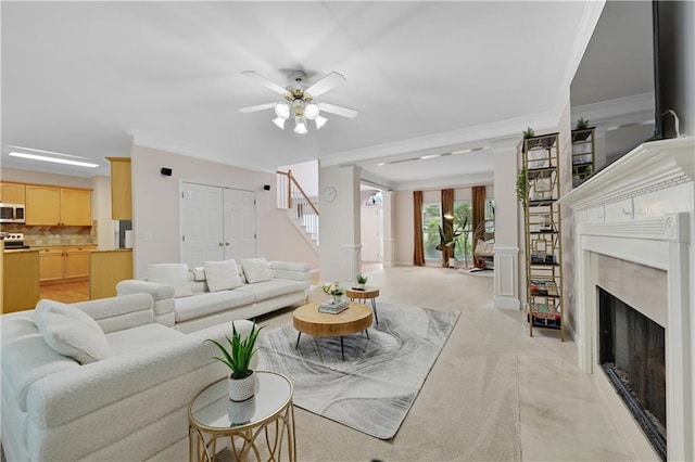 living room featuring crown molding, ceiling fan, a high end fireplace, and light carpet