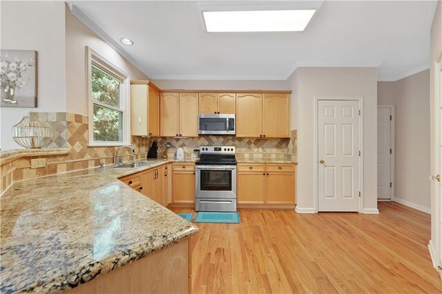 kitchen featuring light stone countertops, appliances with stainless steel finishes, sink, light brown cabinets, and light wood-type flooring