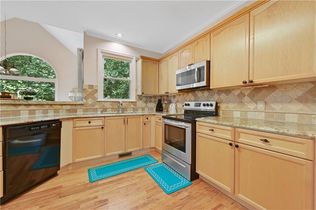 kitchen featuring light hardwood / wood-style flooring, stainless steel appliances, vaulted ceiling, and light brown cabinetry