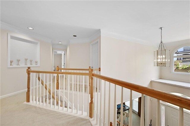 hallway featuring light carpet, ornamental molding, and an inviting chandelier