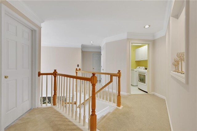 hall featuring light carpet, ornamental molding, and separate washer and dryer