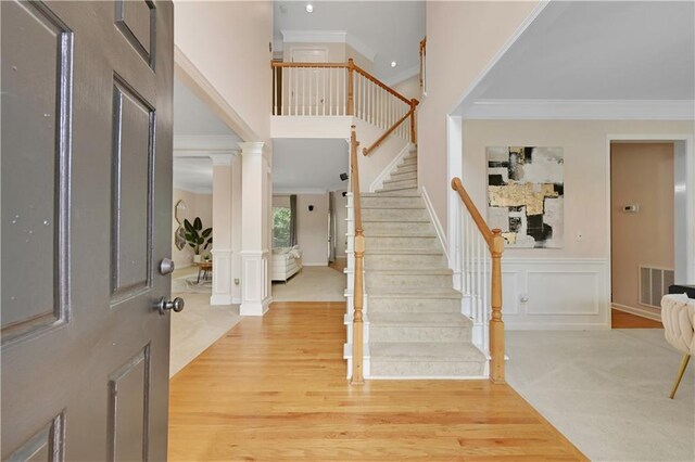 entryway featuring ornamental molding, hardwood / wood-style flooring, and ornate columns