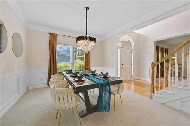 dining room with ornamental molding, an inviting chandelier, and light hardwood / wood-style floors