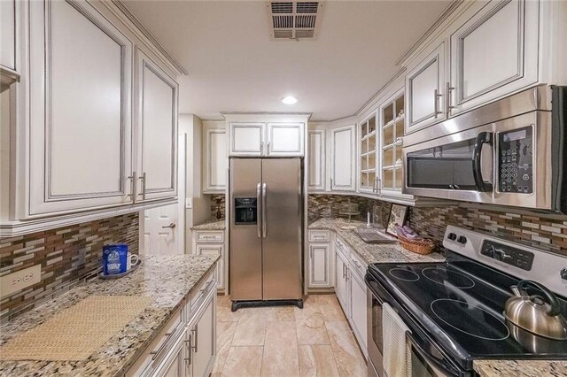 kitchen with backsplash, light stone countertops, and stainless steel appliances