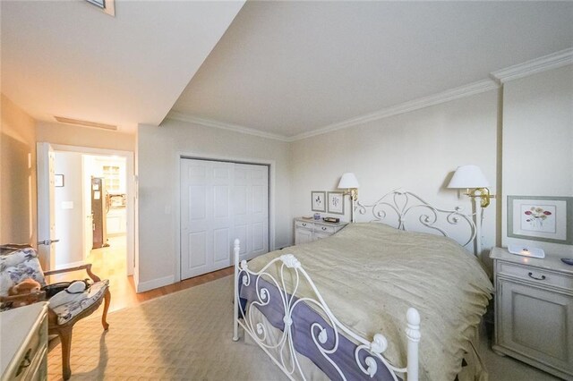 bedroom with light hardwood / wood-style flooring, crown molding, and a closet