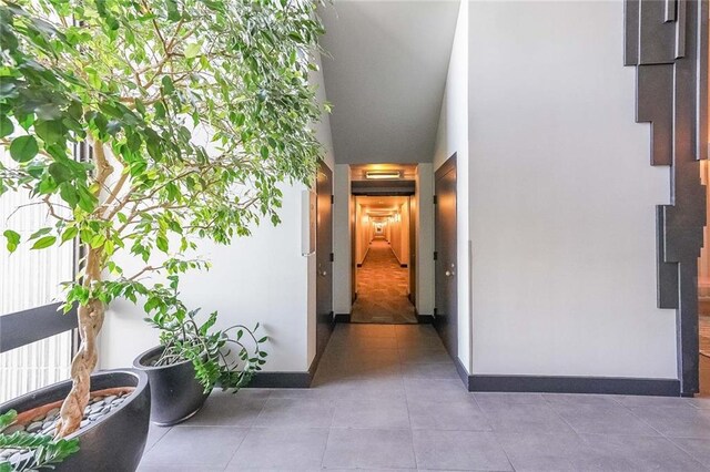 corridor featuring tile patterned floors and vaulted ceiling