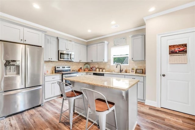 210 Riverpoint Way, Jackson, GA 30233 - kitchen featuring stainless steel appliances, ornamental molding, a kitchen breakfast bar, light wood-style floors, and a kitchen island