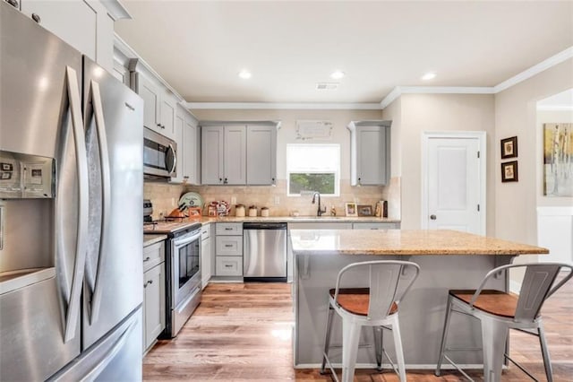 210 Riverpoint Way, Jackson, GA 30233 - kitchen featuring appliances with stainless steel finishes, gray cabinetry, a breakfast bar, ornamental molding, and light wood-style floors