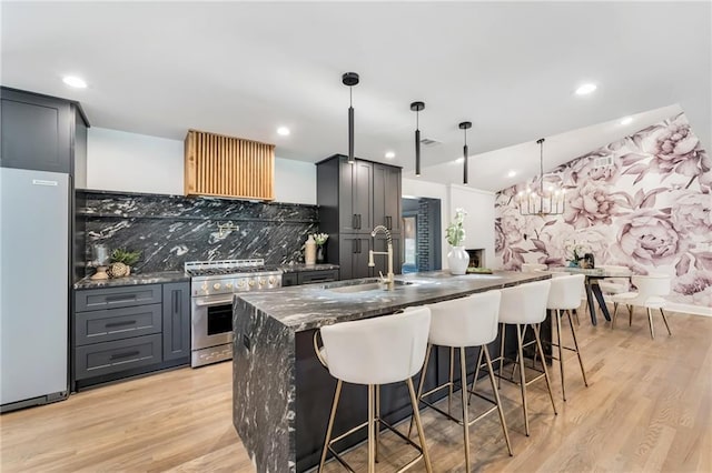 kitchen with pendant lighting, backsplash, sink, high end stainless steel range, and white fridge