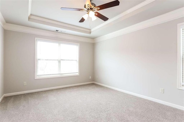 carpeted spare room featuring a tray ceiling, ceiling fan, and crown molding