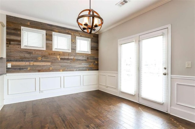 unfurnished dining area featuring dark hardwood / wood-style flooring, ornamental molding, a wealth of natural light, and a chandelier