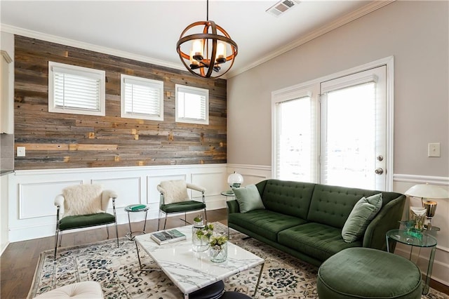 living room featuring dark wood-type flooring, a chandelier, and ornamental molding