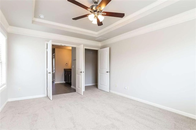 unfurnished bedroom with carpet, a tray ceiling, ceiling fan, and ornamental molding