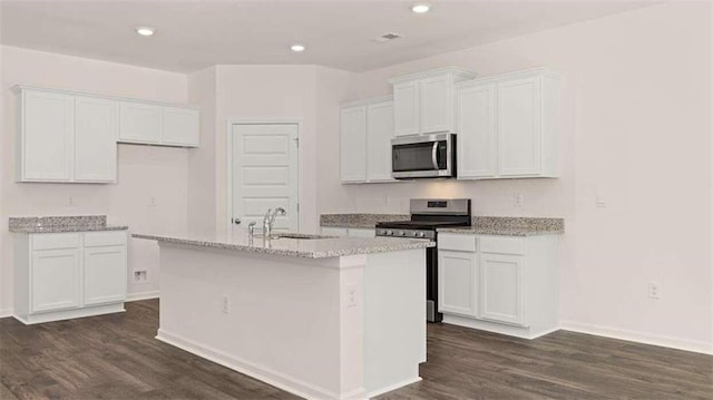 kitchen featuring appliances with stainless steel finishes, dark hardwood / wood-style floors, white cabinetry, sink, and a kitchen island with sink