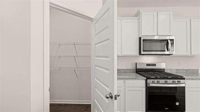 kitchen featuring white cabinetry, appliances with stainless steel finishes, and light stone counters