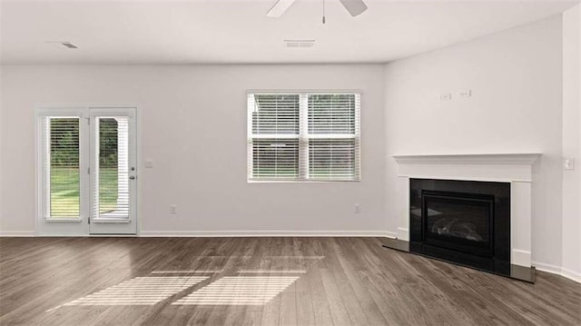 unfurnished living room with ceiling fan, dark hardwood / wood-style flooring, and a wealth of natural light