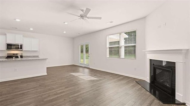 unfurnished living room featuring dark wood-type flooring, ceiling fan, and sink