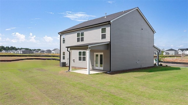 back of property with central AC unit, a patio, and a lawn