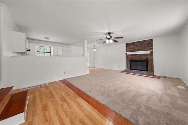 unfurnished living room with a brick fireplace, ceiling fan, and light hardwood / wood-style flooring