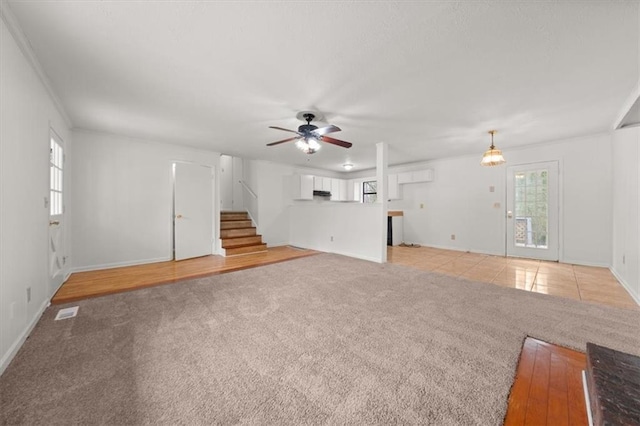 unfurnished living room featuring plenty of natural light, light colored carpet, and ceiling fan