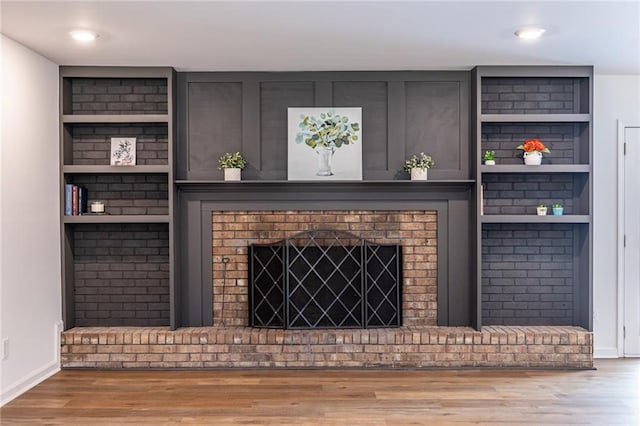 96 Sam Alexander Rd, Douglasville, GA 30134 - living room featuring baseboards, built in shelves, wood finished floors, and a brick fireplace
