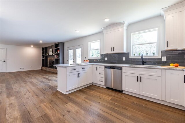 96 Sam Alexander Rd, Douglasville, GA 30134 - kitchen with decorative backsplash, a peninsula, wood finished floors, a sink, and stainless steel dishwasher