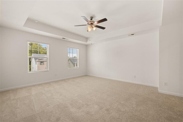 carpeted empty room with a tray ceiling and ceiling fan