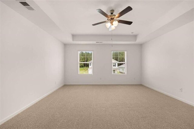 carpeted spare room featuring a raised ceiling and ceiling fan