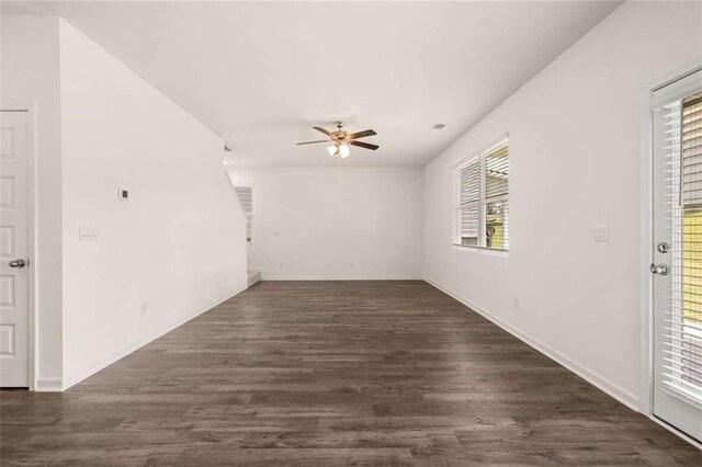 empty room featuring ceiling fan, a healthy amount of sunlight, and dark hardwood / wood-style floors