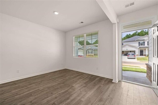 unfurnished room with dark hardwood / wood-style flooring and beamed ceiling