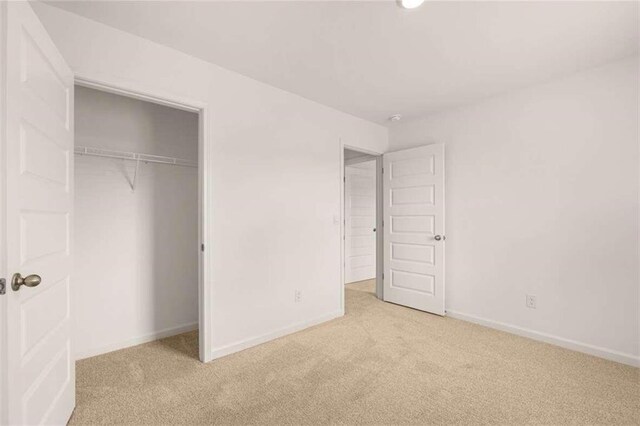 unfurnished bedroom with a closet and light colored carpet