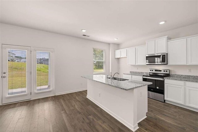 kitchen featuring a kitchen island with sink, white cabinets, light stone counters, and appliances with stainless steel finishes