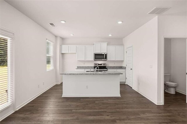 kitchen featuring sink, stainless steel appliances, light stone counters, an island with sink, and white cabinets