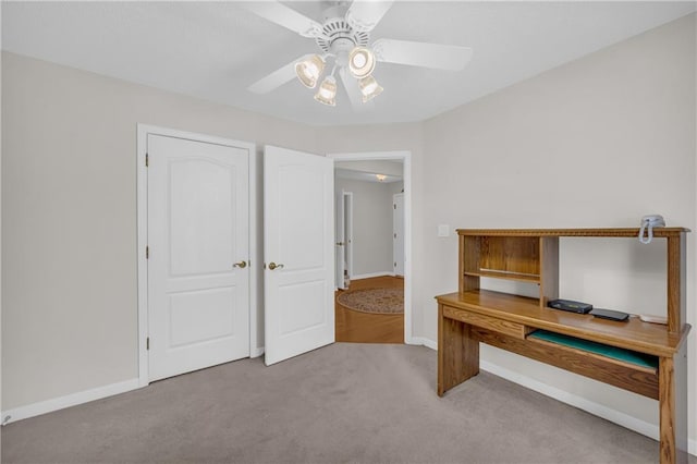 unfurnished office with a ceiling fan, carpet flooring, and baseboards