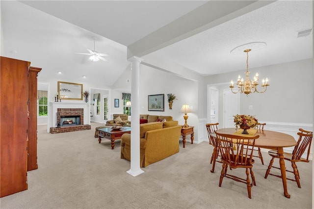 dining space featuring carpet floors, a brick fireplace, lofted ceiling, ceiling fan, and a chandelier