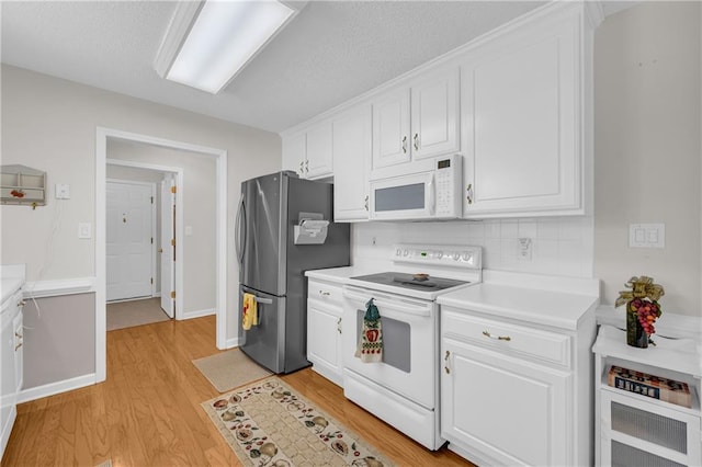 kitchen with white appliances, light wood-style floors, white cabinets, light countertops, and backsplash