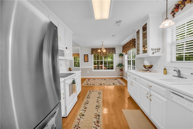 kitchen with white appliances, a sink, white cabinetry, light wood finished floors, and glass insert cabinets